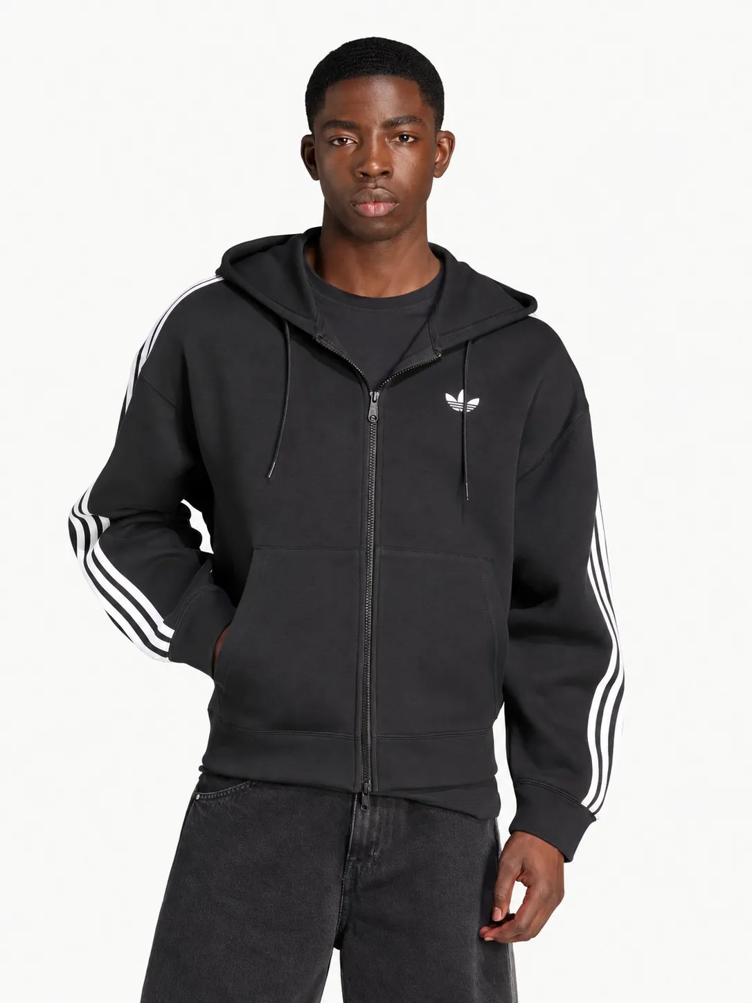 Hoodie Adidas negro puesto y abierto, plano medio de un modelo que lo lleva con camiseta negra y jean negro ancho