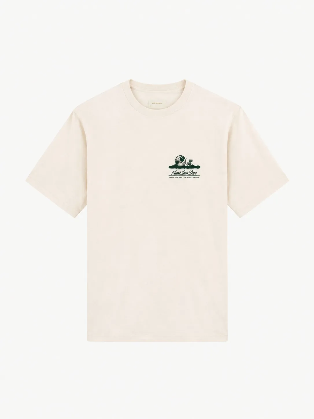 Camiseta Aimé Leon Dore color crudo, vista frontal de la prenda sola con el cuello redondo acanalado y el escudo Unisphere en verde, pequeño, sobre el pecho