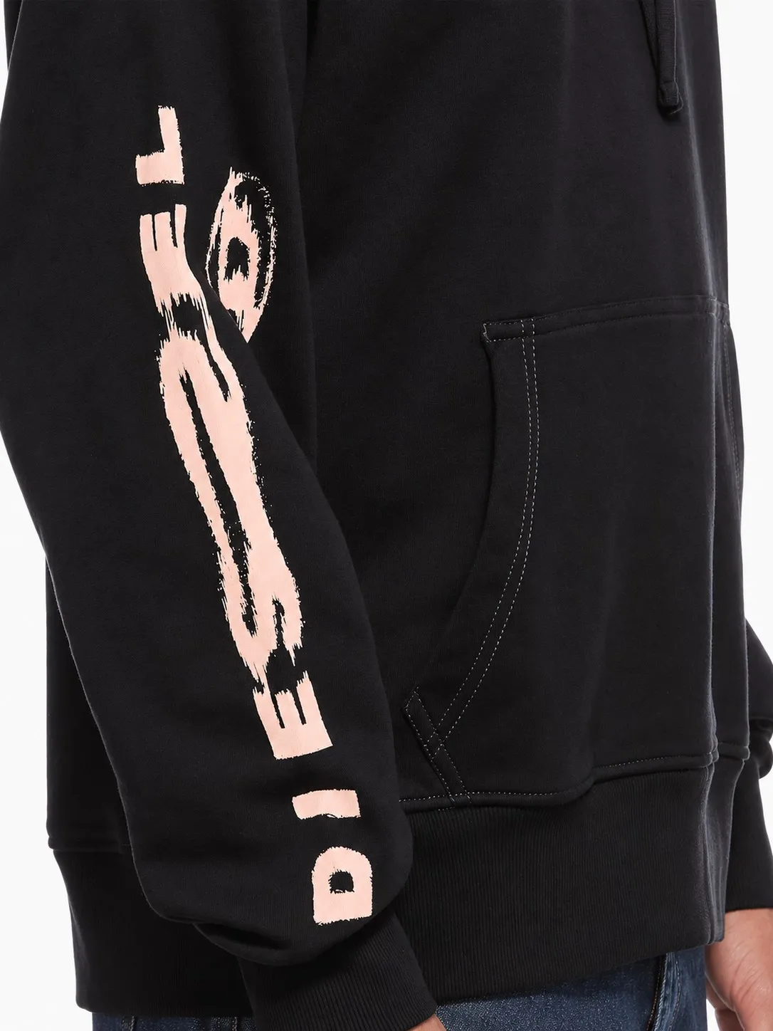 Hoodie Diesel negro puesto, detalle de la manga con el logo Diesel en rosa y el bolsillo canguro