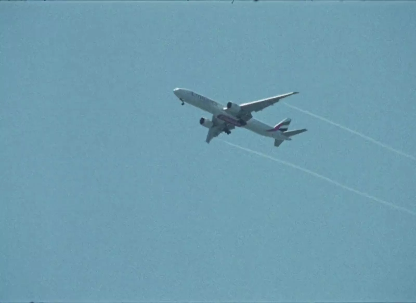 Un avión cruza un cielo azul dejando dos estelas