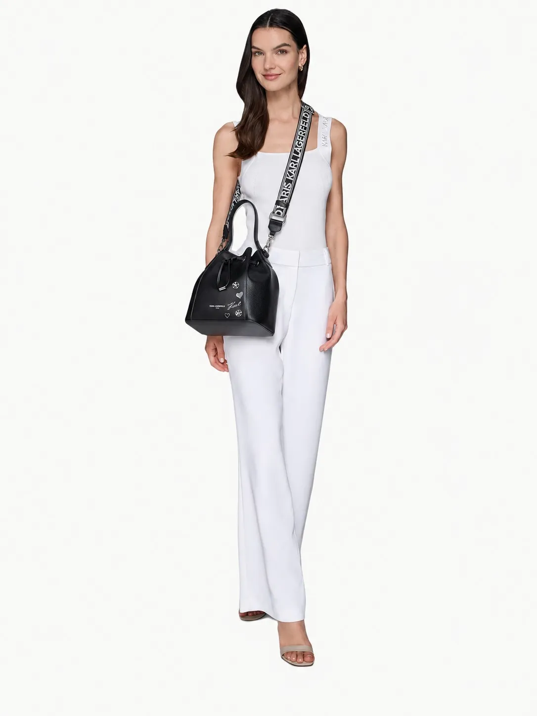 Modelo de cuerpo entero con el bolso Karl Lagerfeld negro cruzado con la correa del logo, top y pantalón blancos