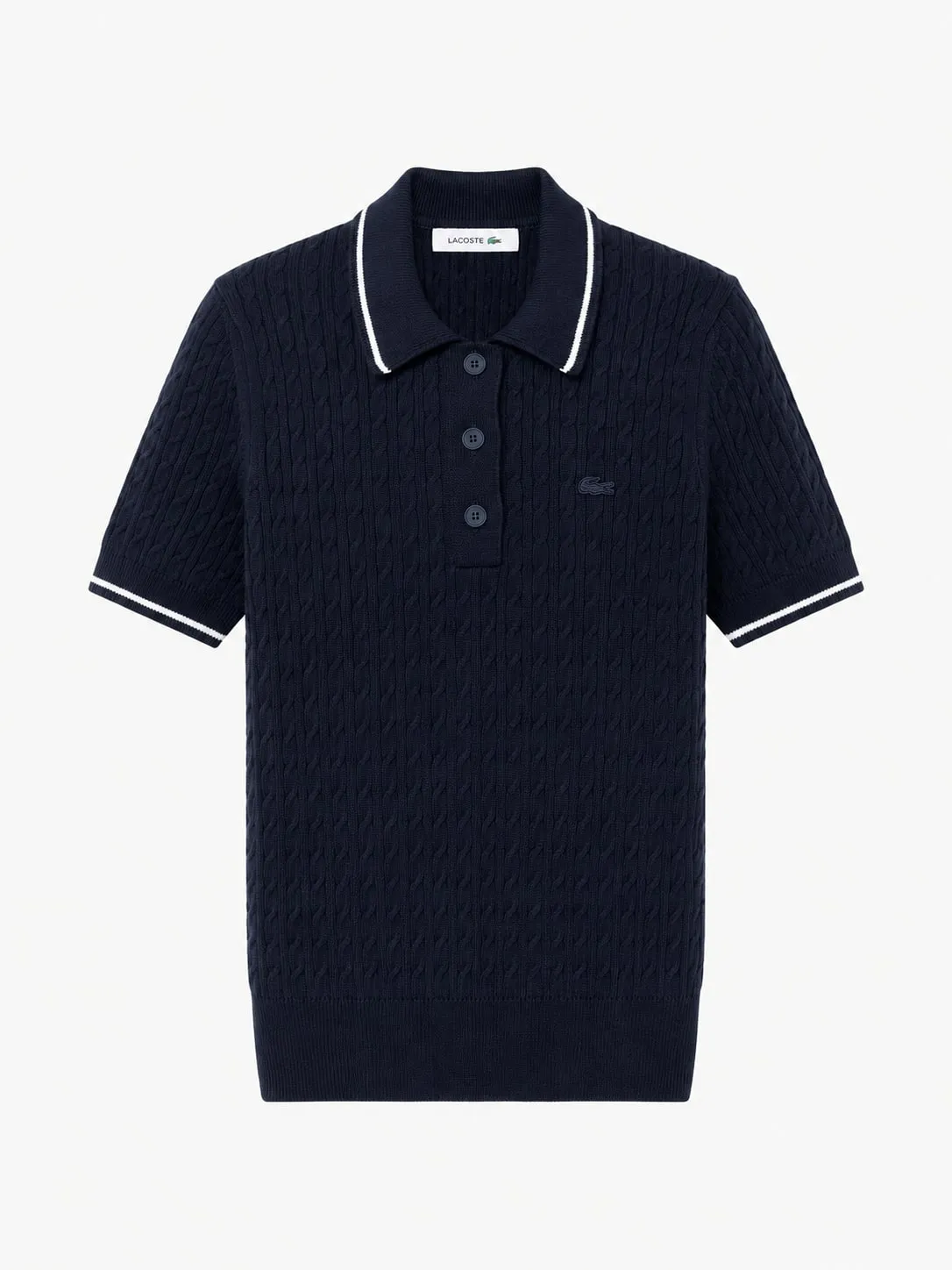 Polo Lacoste de punto trenzado azul marino, vista frontal de la prenda sola con el cuello ribeteado en blanco, tres botones y el cocodrilo bordado en el pecho