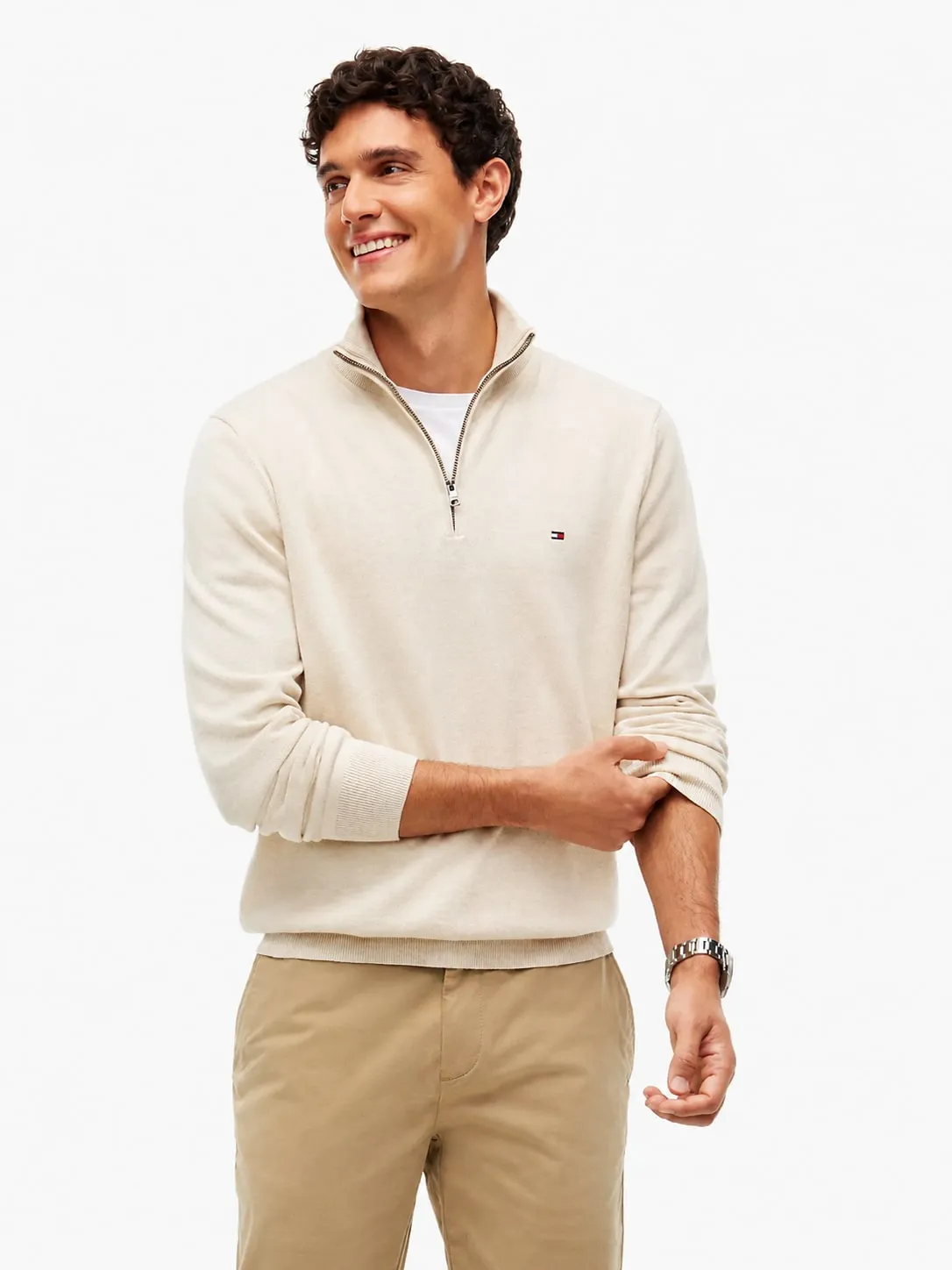Buzo Tommy Hilfiger beige puesto, plano medio de un modelo que lo lleva con una camiseta blanca debajo y pantalón chino