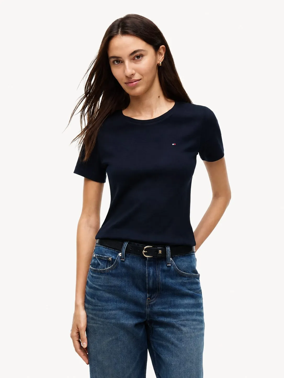 Camiseta Tommy Hilfiger azul marino puesta, plano medio de una modelo que la lleva por dentro de unos jeans con cinturón negro